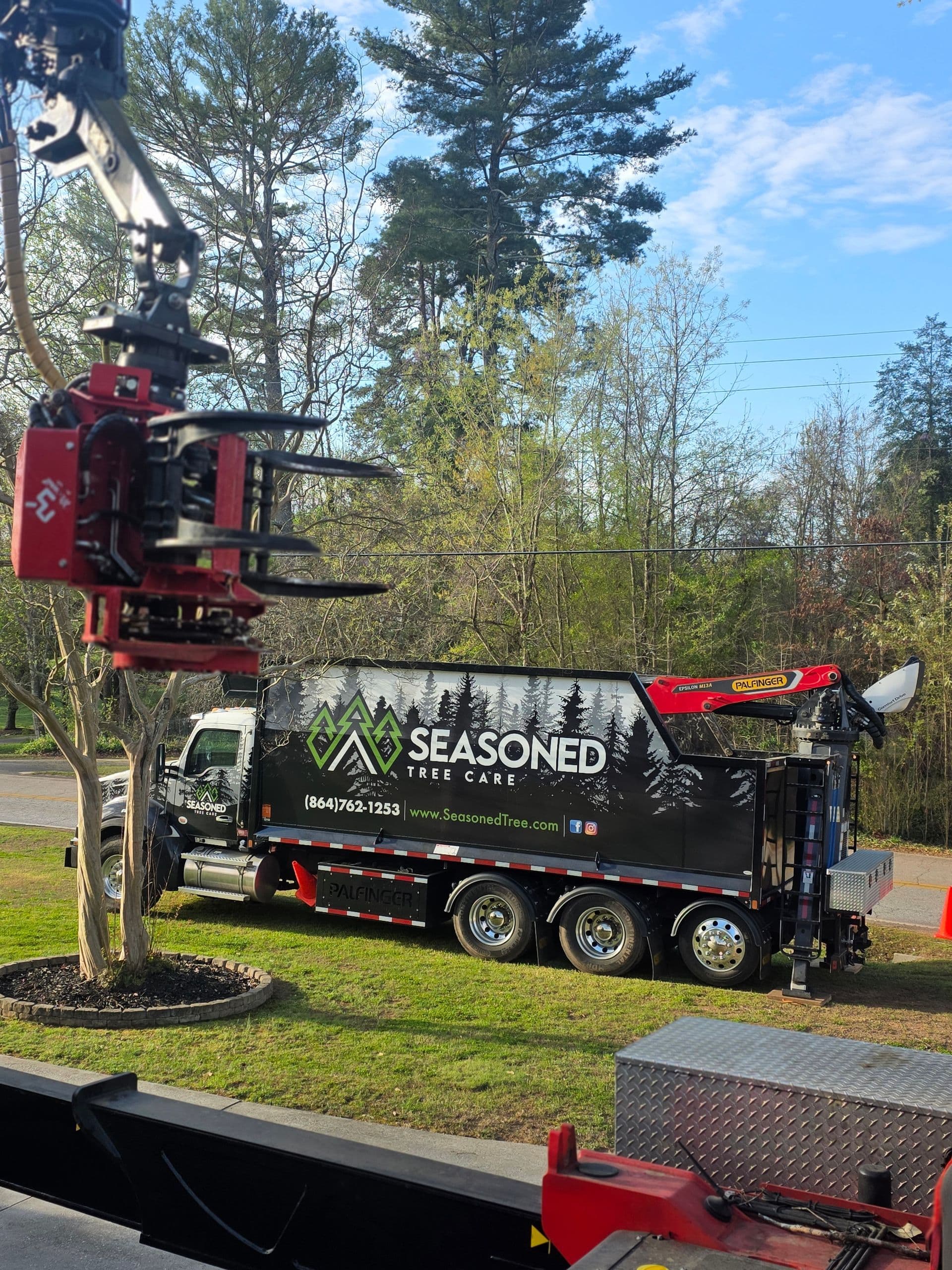 Seasoned Tree Care crane lifting a large tree section over a property