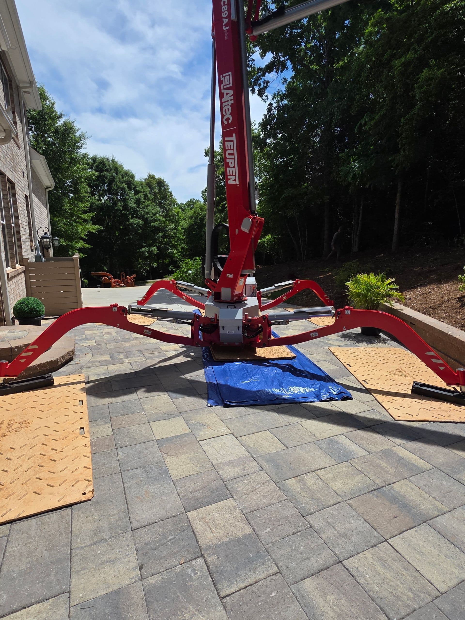 Compact spider lift working a tree removal beside a home
